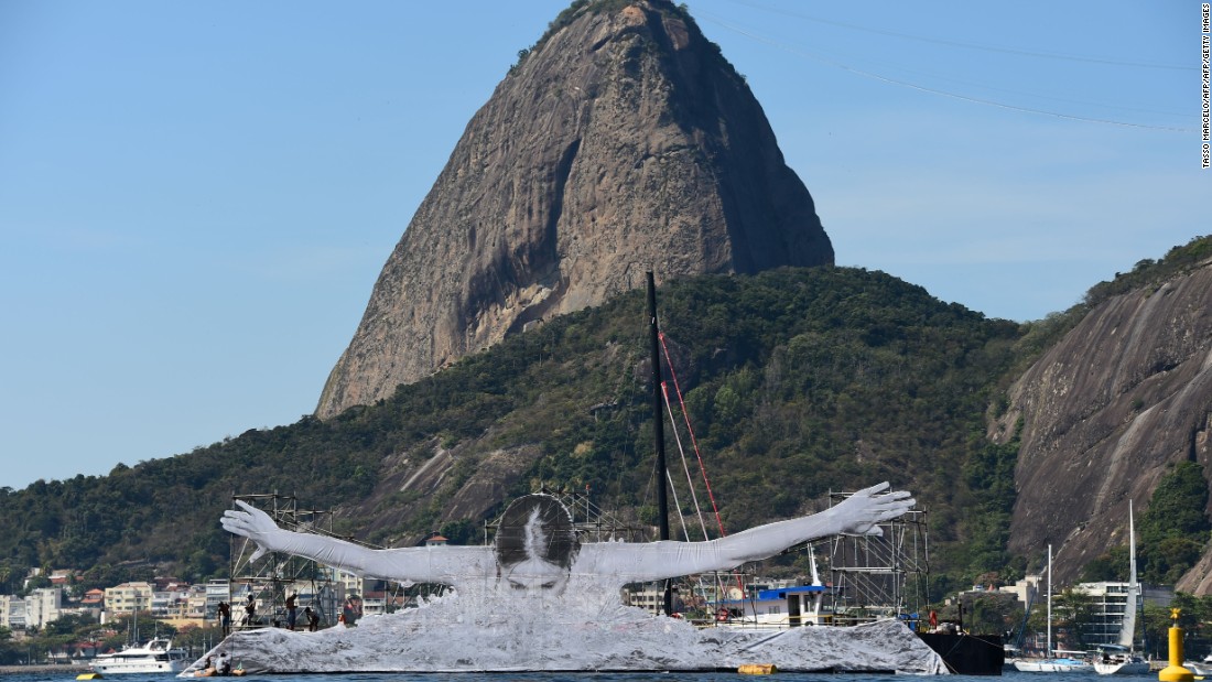 To date, JR has revealed four massive installations, each of which pay tribute to Olympic athletes: a swimmer in Guanabara Bay, a diver at Barra Beach, a crescent moon atop a residence for artists, and a high-jumper bending back over a building in the Flamengo neighborhood.