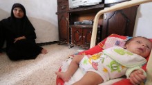 Umm Mahmud sits next to her baby Mahmud Idilbi in Aleppo after a member of Syria Civil Defence rescued him from under the rubble of a building.