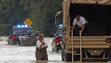 Jeff Robinson lowers a ladder from a National Guard truck as his wife wades through floodwaters near their home in Baptist, Louisiana, on August 13.
