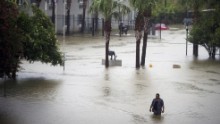 A resident wades through floodwaters at apartments near Louisiana State University in Baton Rouge.