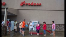 Eli Turnage hands out water to people waiting in line at Carter's Supermarket in Livingston on August 15.