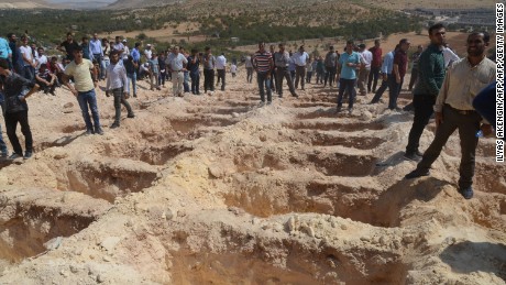 People wait Sunday near freshly dug graves for the victims of the Gaziantep blast.