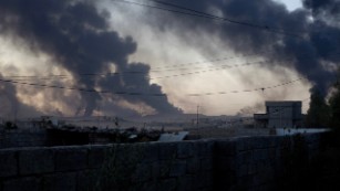 Smoke rises from al-Qayyara in the late afternoon light, as ISIS burns crude oil to block visibility from above.