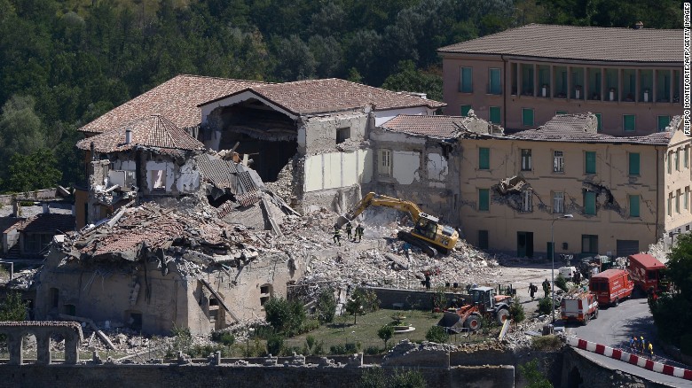 Rescue and emergency service personnel use an excavator to search for victims under the remains of a building in Amatrice on August 25.