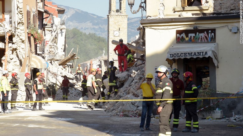Firefighters and rescue workers stand near the damaged Sant&#39;Agostino church and a destroyed ice cream shop in the Italian village of Amatrice on Friday, August 26.