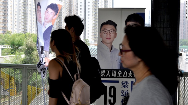 Commuters walk past signs bearing Edward Leung&#39;s face in Hong Kong&#39;s New Territories East constituency.