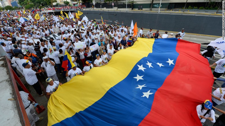 Opposition protesters unfurl a Venezuelan flag at a protest in Caracas.