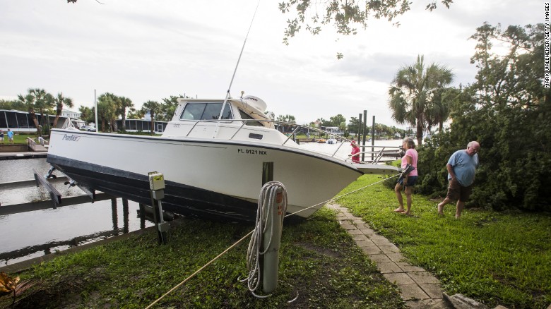 People check damage to a boat in their neighborhood in Shell Point Beach, Florida. 