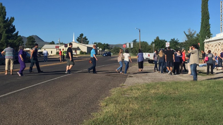 People cross a street as Alpine High School is evacuated following a shooting there Thursday morning.