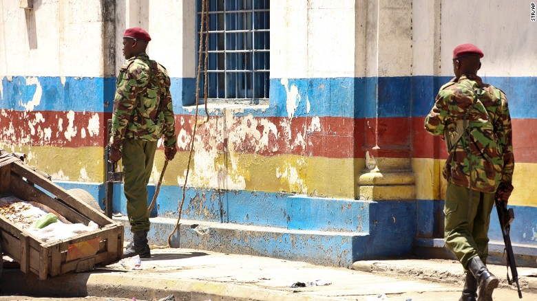 Armed officers patrol outside the police station.