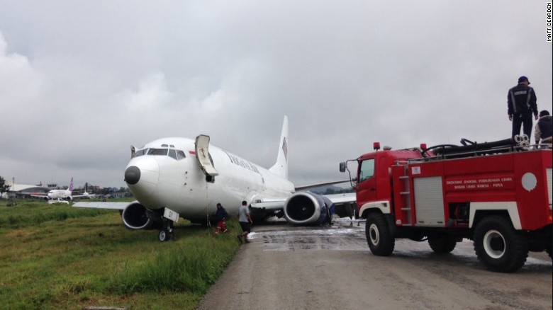 Fire crews attend to a Trigana Air Services flight which violently skidded off the runway.