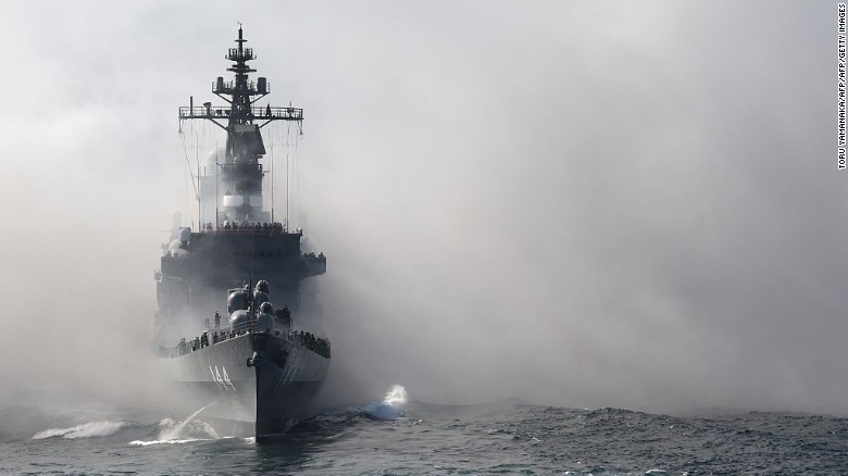 Japan&#39;s Maritime Self-Defense Force (MSDF) escort ship Kurama sails through smoke during a fleet review off Sagami Bay, Kanagawa prefecture, on October 18, 2015.