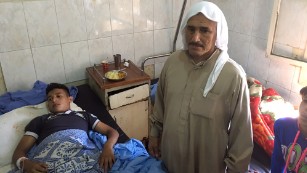 Mahmud Jassim, 16, receives treatment at Aleppo. His  father is by his side.
