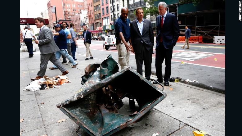 New York Mayor Bill de Blasio, right, and New York Governor Andrew Cuomo, second right, look over the mangled remains of a dumpster on Sunday, September 18, while touring the site of an explosion in New York&#39;s Chelsea neighborhood that injured 29 people. 