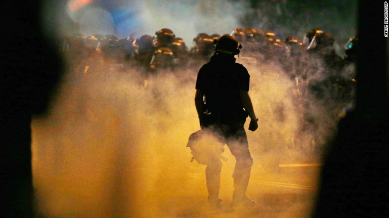Police fire teargas as protestors converge on downtown following Tuesday's police shooting of Keith Lamont Scott in Charlotte, N.C., Wednesday, Sept. 21, 2016. Protesters have rushed police in riot gear at a downtown Charlotte hotel and officers have fired tear gas to disperse the crowd. At least one person was injured in the confrontation, though it wasn't immediately clear how. Firefighters rushed in to pull the man to a waiting ambulance.(AP Photo/Gerry Broome)