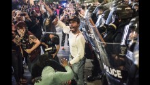 A protester shouts to a crowd in downtown Charlotte, North Carolina, on the evening of Wednesday, September 21. Violent protests erupted the night before following the death of Keith Lamont Scott, who was shot in an apartment complex parking lot while police tried to serve a warrant for a different man. Charlotte-Mecklenburg Police Chief Kerr Putney said Scott exited his car with a gun and that he was shot after he wouldn't drop it. Scott's family said he was unarmed and sitting in his car reading a book.