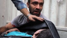 A Syrian man carries the body of his nephew, recovered from the rubble.