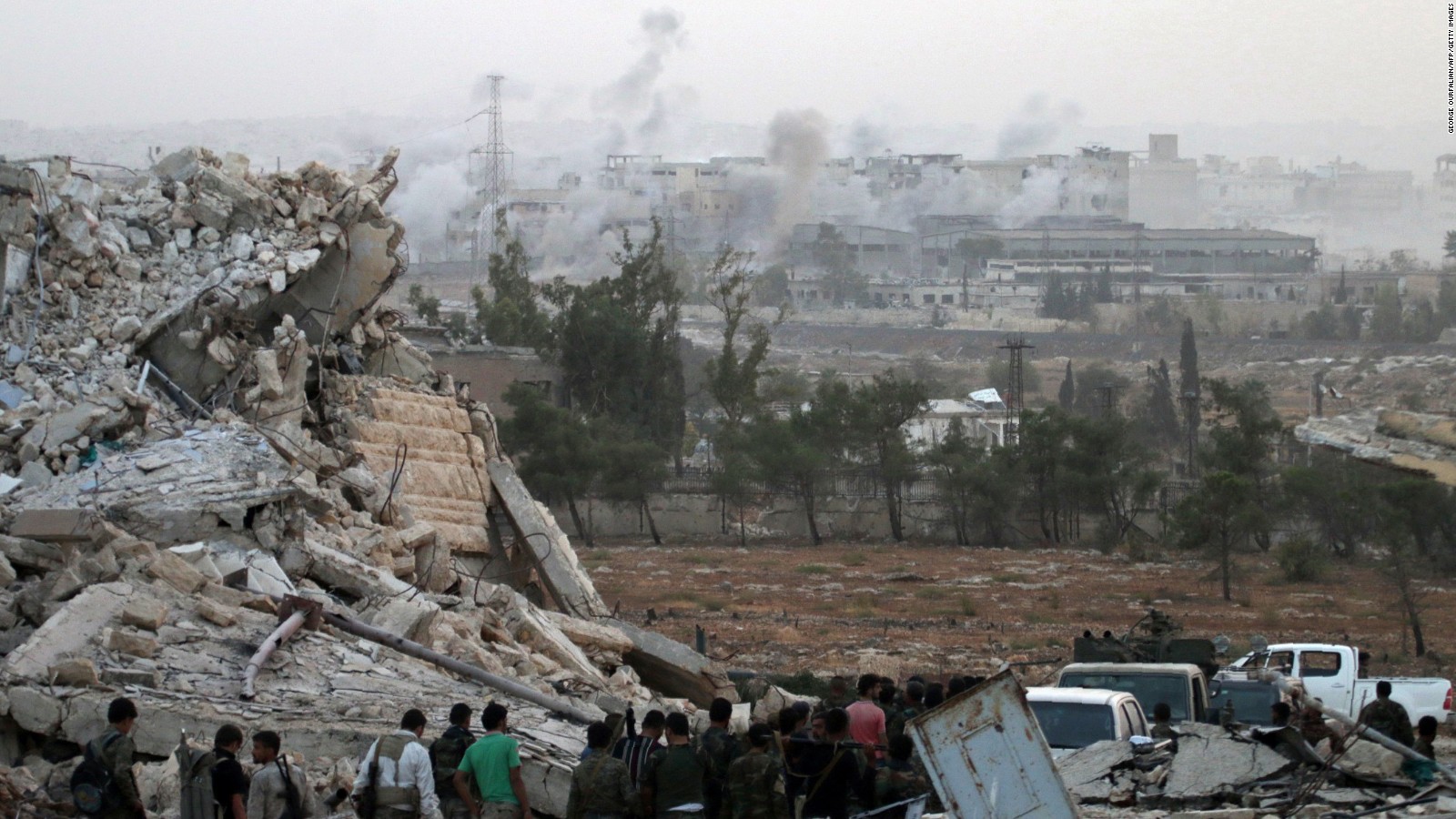Syrian regime forces gather at the Kindi Hospital as smoke billows following airstrikes on Aleppo on October 2, 2016.