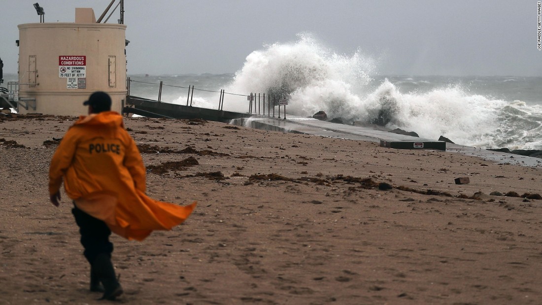 A police officer walks along the beach as waves crash ashore as Hurricane Matthew approaches  on Thursday, October 6, in Singer Island, Florida. 