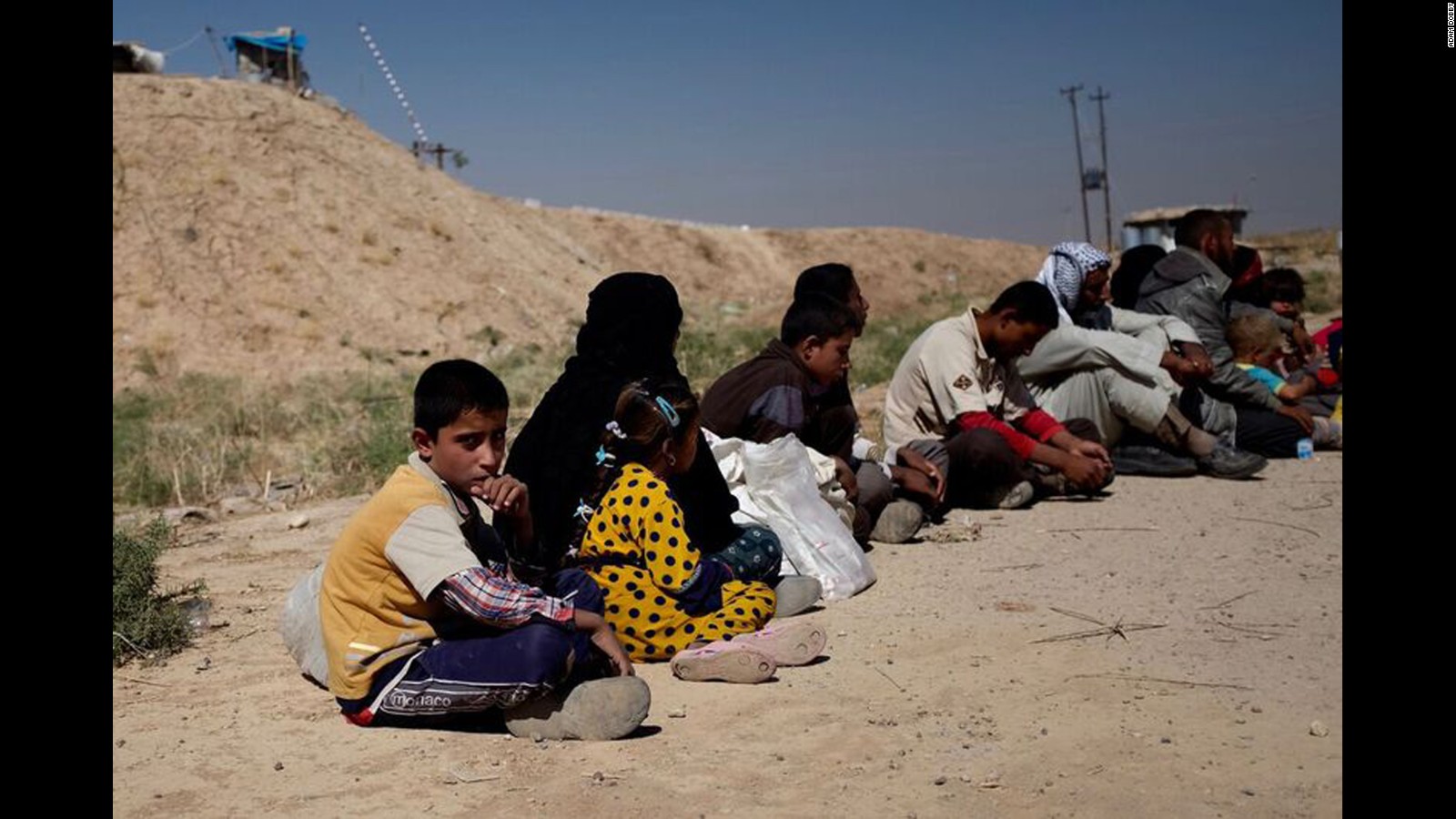 Families fleeing from their homes near the ISIS-controlled town of Hawija wait to be trucked away from the front line.