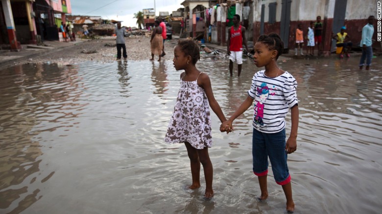 Girls wade through a flooded street in Les Cayes on Thursday, October 6.
