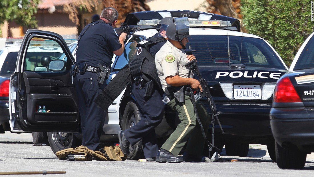 Police watch a home in Palm Springs, California, where authorities say three officers were shot.