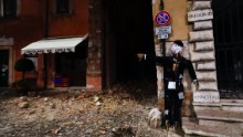 A Halloween dummy rests on a wall in front of earthquake damage in Visso.