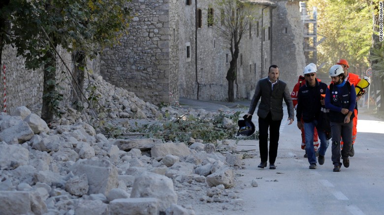 Italian civil protection staff pass a collapsed wall Sunday in Norcia after the quake jolted central Italy.