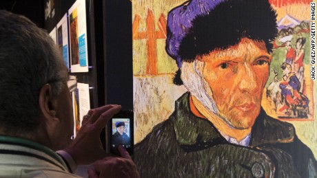A visitor takes pictures of the art exhibition 'Van Gogh Alive' in Tel Aviv. Self-Portrait with Bandaged Ear by Dutch artist Vincent Van Gogh.