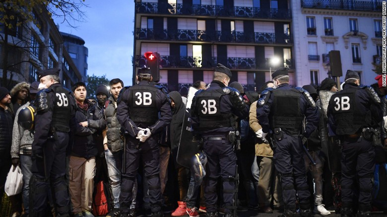 A line of police restrain migrants during Friday morning&#39;s evacuation of the camp in Paris. 