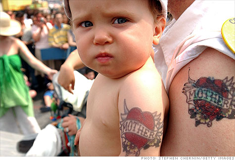 A baby sports a 'Mother' tattoo like his dad's as he's carried through