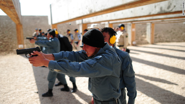 Afghan police trainees practice using their guns as a German policeman watches near Camp Marmal in Afghanistan.