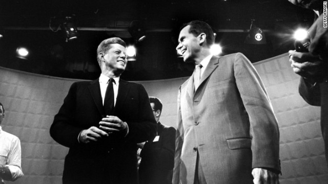 John F. Kennedy and Richard Nixon 
exchange smiles beneath glaring lights before their first TV debate in 1960. 