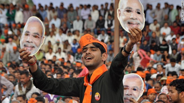An Indian supporter Narendra Modi holds up masks of the prime ministerial candidate at an election rally.