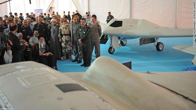 Iranian Supreme Leader Ayatollah Ali Khamenei, seated left, listens to an official during his visit to an aerospace exhibition in Tehran, Iran, on Sunday, May 11. The exhibition revealed an advanced CIA spy drone, at front, captured in 2011 by Iran, and its Iranian-made copy, at back.