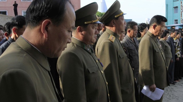 North Korean officials stand among the families of victims of the building collapse in Pyongyang, North Korea, on May 17.