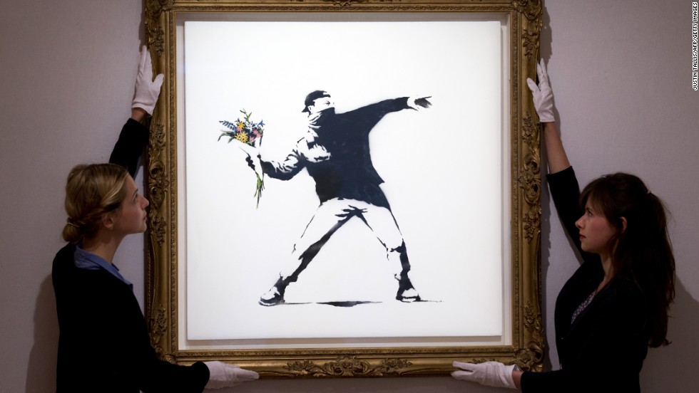 Gallery assistants adjust Banksy&#39;s &quot;Love Is in the Air&quot; ahead of an auction in London in June 2013. The piece was sold for $248,776.