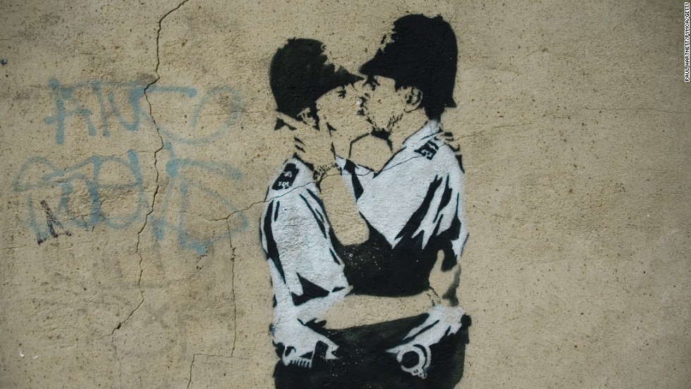 A stenciled image of two policemen kissing is seen in London in 2005. &quot;Kissing Coppers&quot; is one of Banksy&#39;s most famous works. Click through the gallery for a look at some of his other notable pieces.