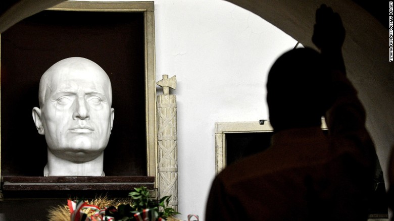 A far-right miliant makes a Fascist salute at Mussolini's tomb at a rally in 2012. 