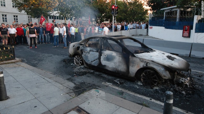 Turkish people look at a burned car in Istanbul on Saturday.