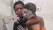 A harrowing video shows two boys crying and wrapping their arms around each other after a barrel bomb killed at least 13 people in Aleppo.