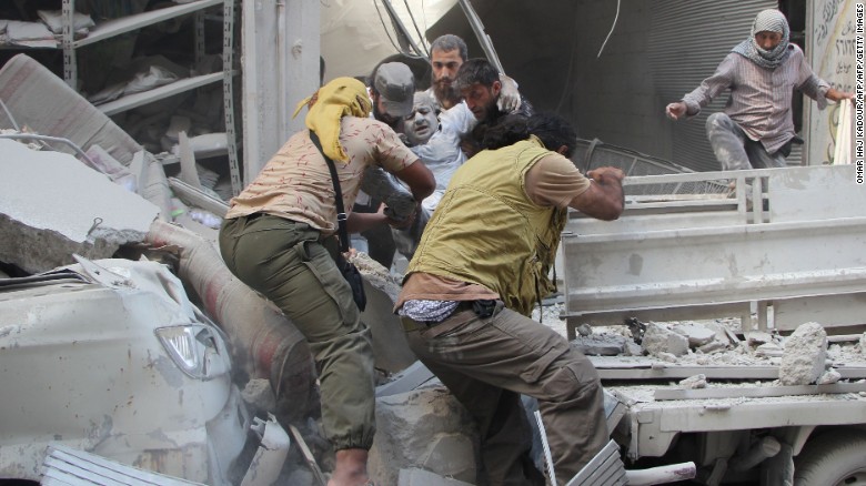 Syrian men evacuate a victim from the rubble of a building following an airstrike on the rebel-held northwestern city of Idlib on September 10, 2016.