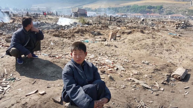 A young North Korean boy sits amid a flood-ravaged landscape in Hamgyong province.