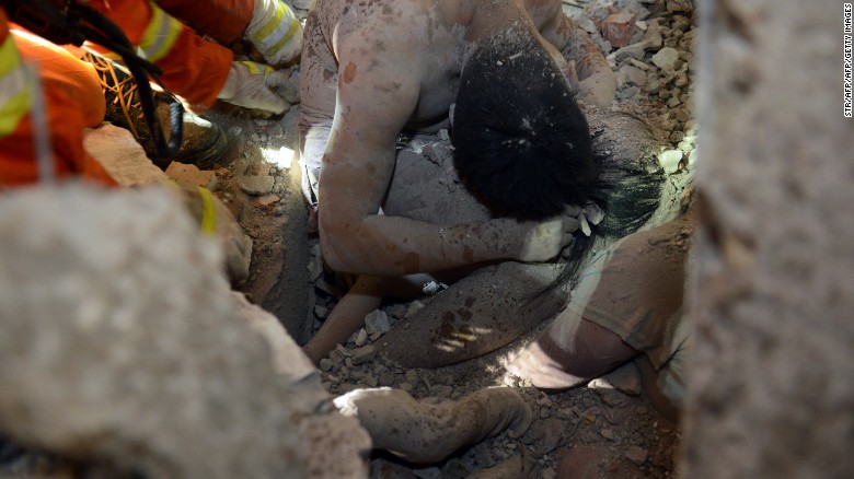 Rescuers try to save a young survivor who was protected by the body of her parents at an accident site after four buildings caved in during the early hours in Wenzhou in eastern China&#39;s Zhejiang province. 