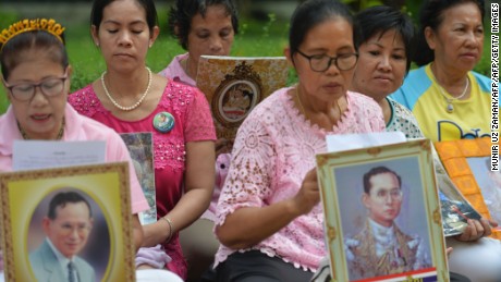 Women hold portraits of Thai King Bhumibol Adulyadej as they pray for his health at Siriraj Hospital, where the king is being treated, in Bangkok on October 12, 2016.