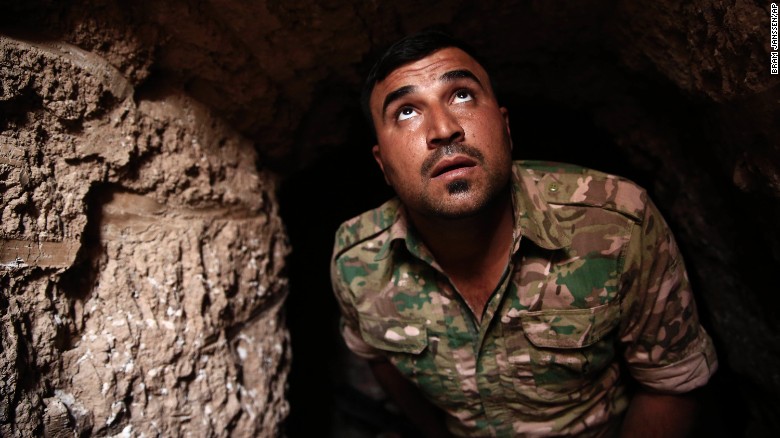 A Peshmerga fighter looks out of the entrance of an ISIS tunnel in Badana.