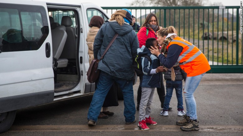 Care workers bring child migrants to a reception point outside the Jungle migrant camp before boarding buses to refugee centres around France.