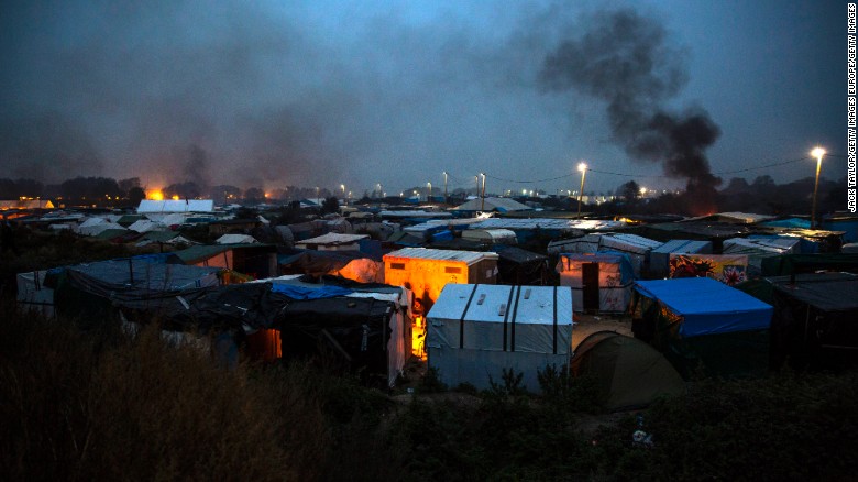 Bonfires illuminate the night sky as night falls on the Jungle migrant camp on October 24, 2016.