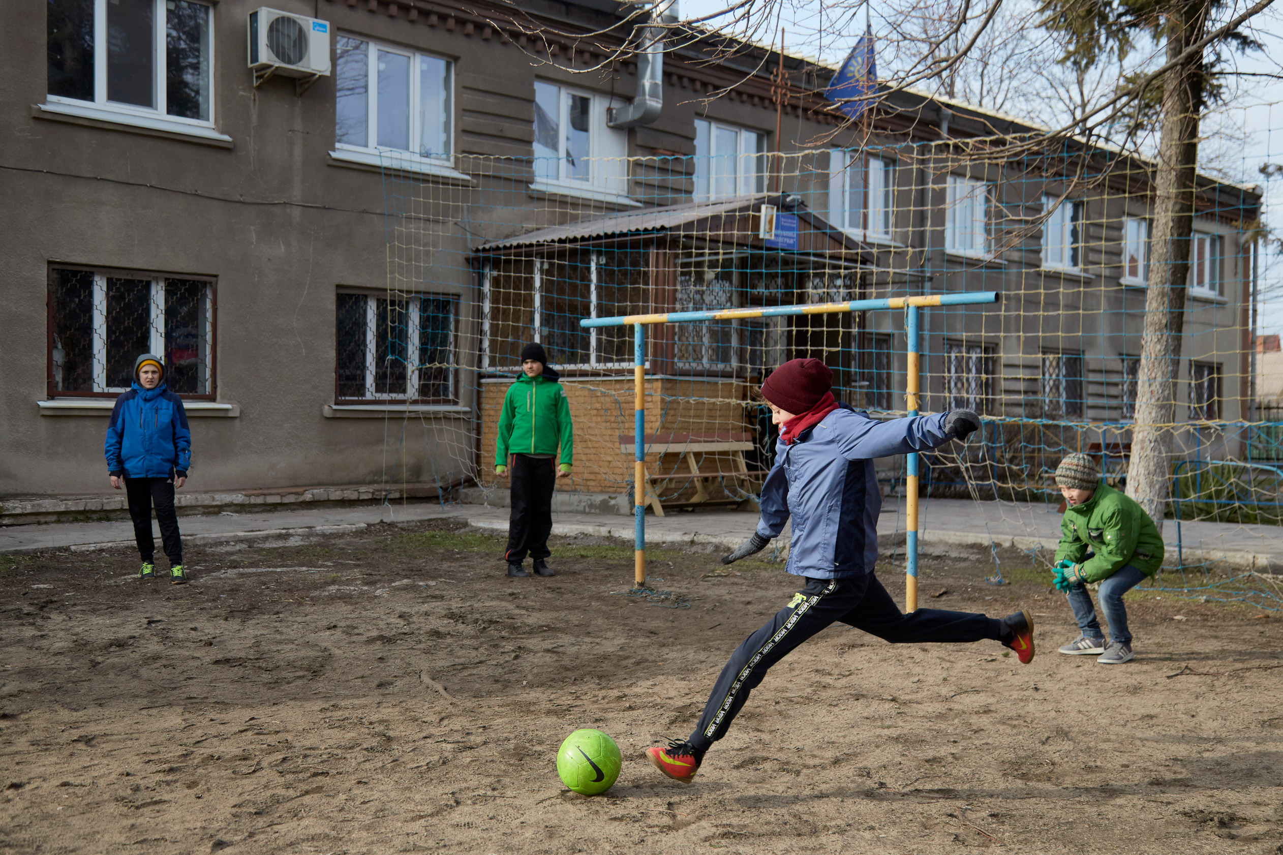 A young child kicks a football with three others in front of a house