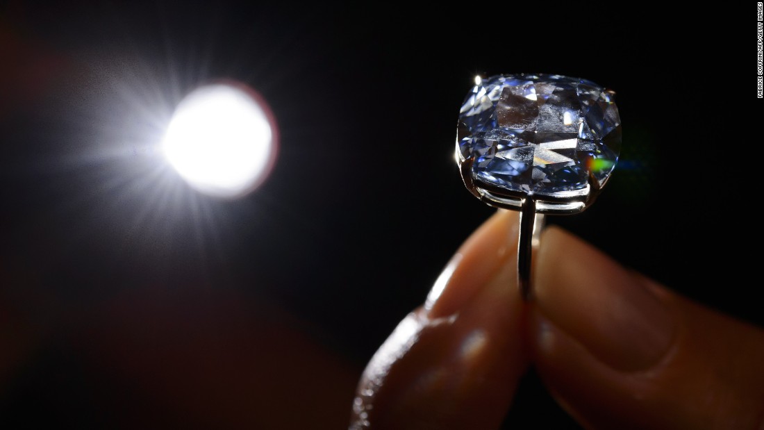 A model holds a 12.03-carat blue diamond during a press preview by auction house Sotheby's in Geneva on November 4, 2015. A 12.03-carat blue diamond could fetch a record $55 million (47 million Euros) when it goes under the hammer by Sotheby's on November 11 in Geneva. Categorised as a fancy vivid blue diamond, the Blue Moon, discovered in South Africa in January last year, is the largest cushion-shaped stone in that category to ever appear at auction. AFP PHOTO / FABRICE COFFRINI (Photo credit should read FABRICE COFFRINI/AFP/Getty Images)